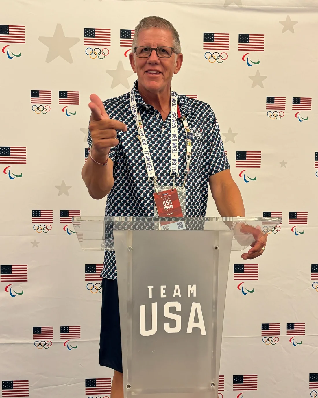 Professor Wagner at Team USA House, standing at the podium against an Olympic and Paralympic backdrop